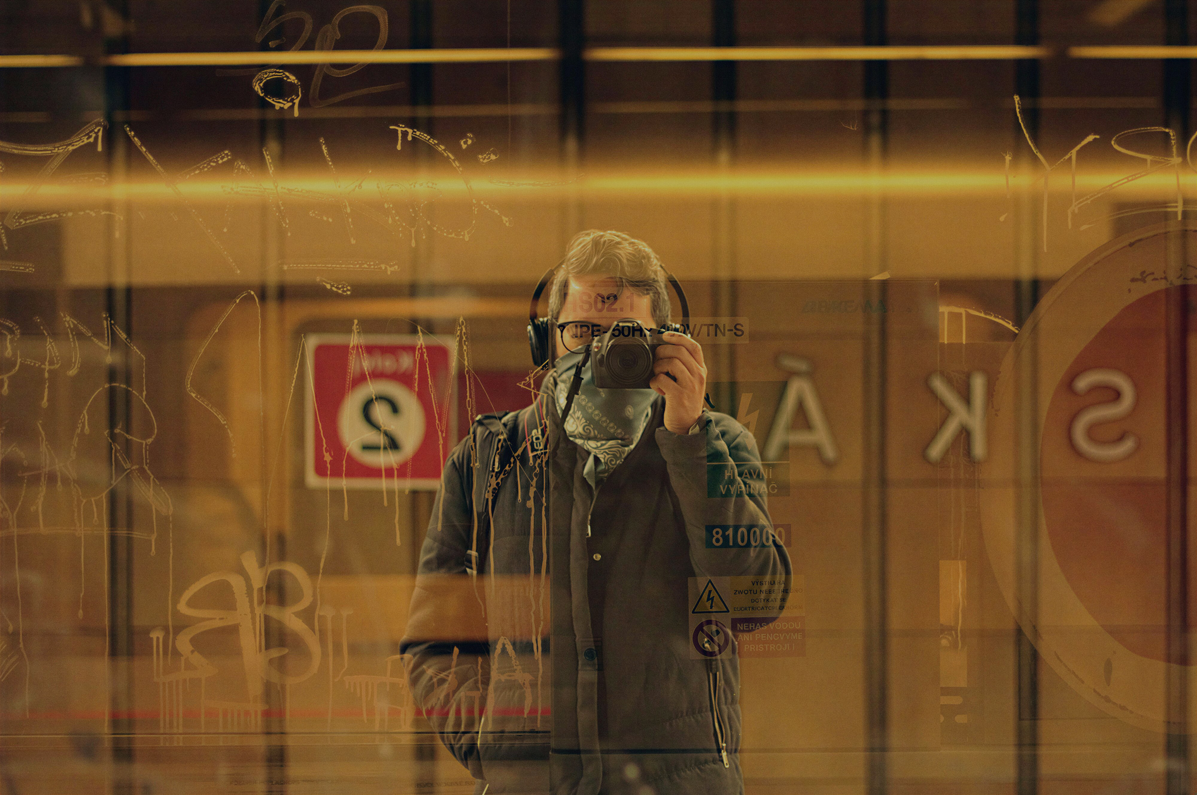 Odair Faléco reflected in a city window with a camera